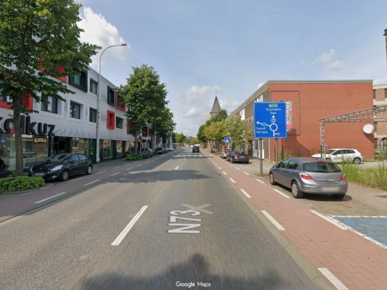 Straatzicht van N73 met auto's geparkeerd langs trottoirs en een verkeersbord richting Tessenderlo en Ham. (vergroot foto)